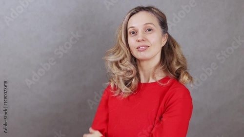 Attractive girl smiling on gray background, showing heart with hands