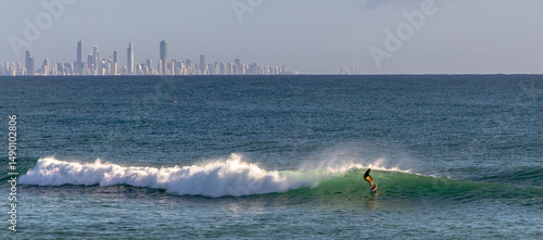 A lone surfer at Coolangatta Beach with the high-rise buildings of Surfer's Paradise in the background.
Gold Coast, Queensland, Australia.