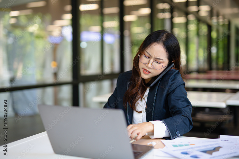 Stressed businesswoman sitting at desk with laptop, tablet computer under work stress worrying about digital investment marketing plan Stressed businesswoman sitting at desk with laptop, tablet computer under work stress worrying about digital investment marketing plan