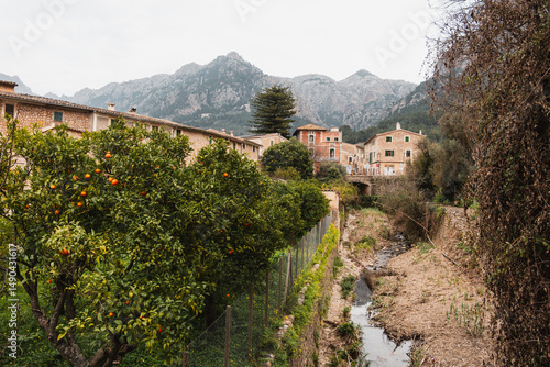 Sóller, Mallorca, Spain - Orange Trees, a creek and Stone Houses in Sóller, Mallorca. Serene Winter without snow. Landscape with Mountain Backdrop