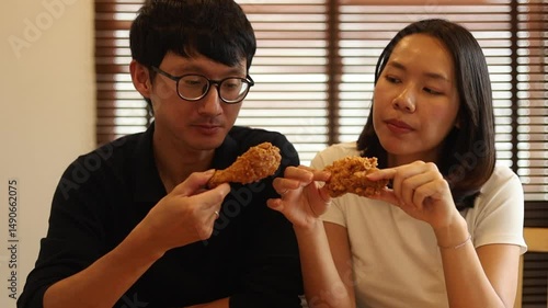 Slow motion scene girlfriend and boyfriend having fried chicken together on weekend. A couple enjoying and cheerful during lunch in living room at home