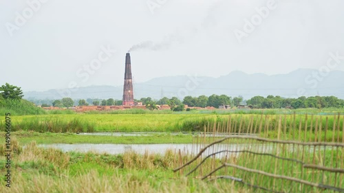 Landscape view of a paddy field and a brick kiln in the distance