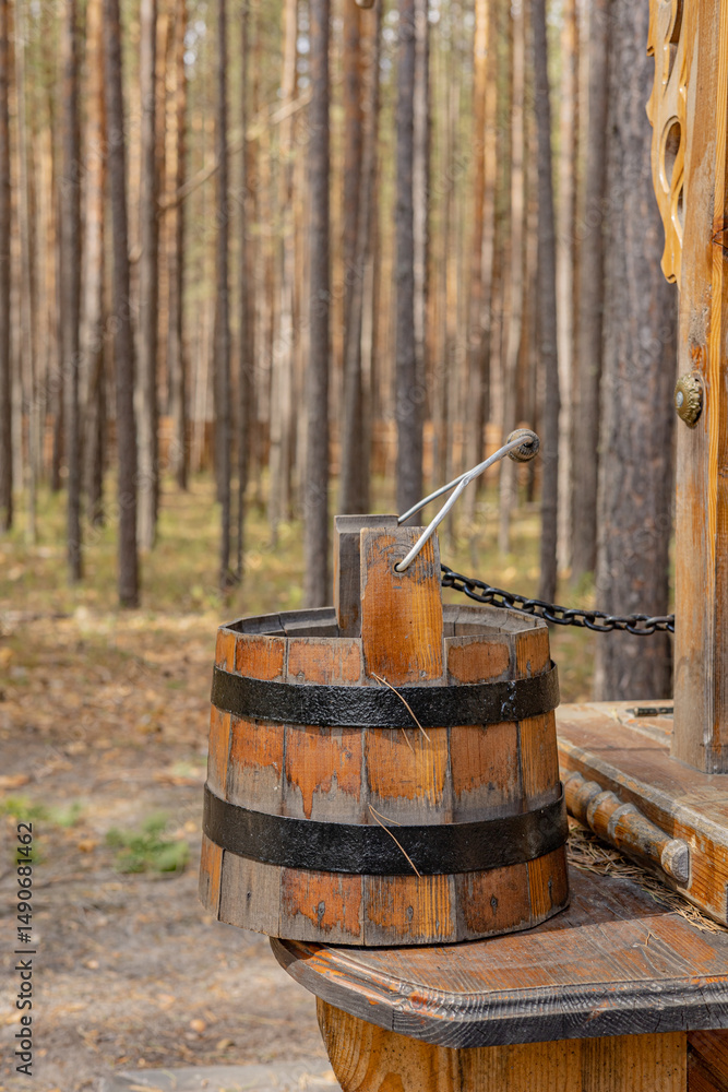 Wooden barrel with a metal handle on a wooden bench in a forest environment. Rural and rustic atmosphere. Wooden barrel with a metal handle on a wooden bench in a forest environment. Rural and rustic atmosphere.