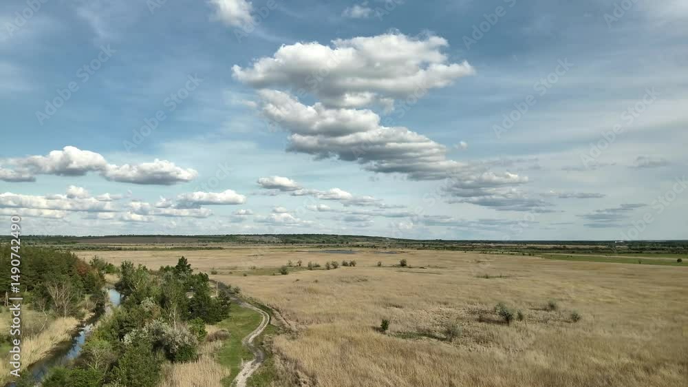 Wide 4K drone shot of nature: river, forest, steppe, and sky filled with dynamic cloud patterns. Wide 4K drone shot of nature: river, forest, steppe, and sky filled with dynamic cloud patterns.
