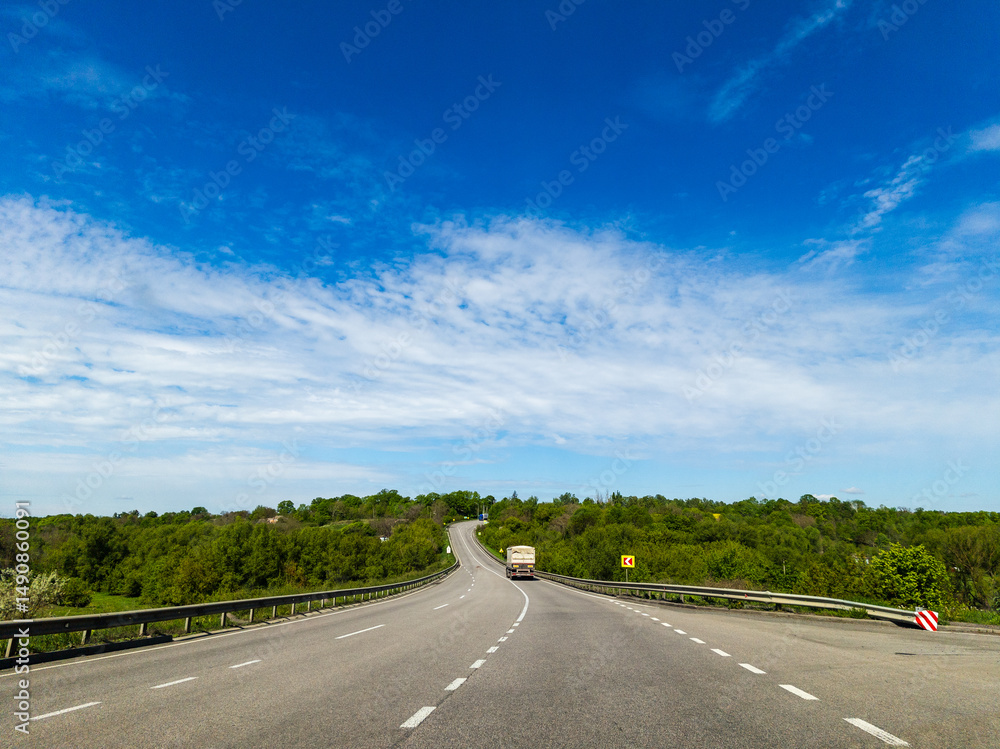 Fototapeta premium A truck driving down a highway with trees in the background