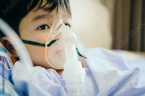 Boy 4 years old , inhale medication by inhalation mask to cure Respiratory Syncytial Virus (RSV) on hospital bed. Admitted patient boy inhalation therapy.