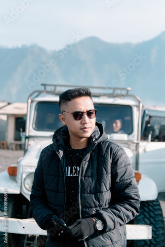 Young Asian Man Posing in Front of Off Road Jeep in the Volcanic Landscape of Mount Bromo East Java Indonesia Adventure Travel Scene