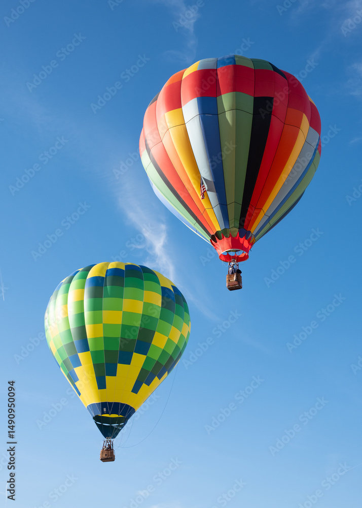 Fototapeta premium A pair of giant colorful hot air balloons rise over blue skies in Northern California.