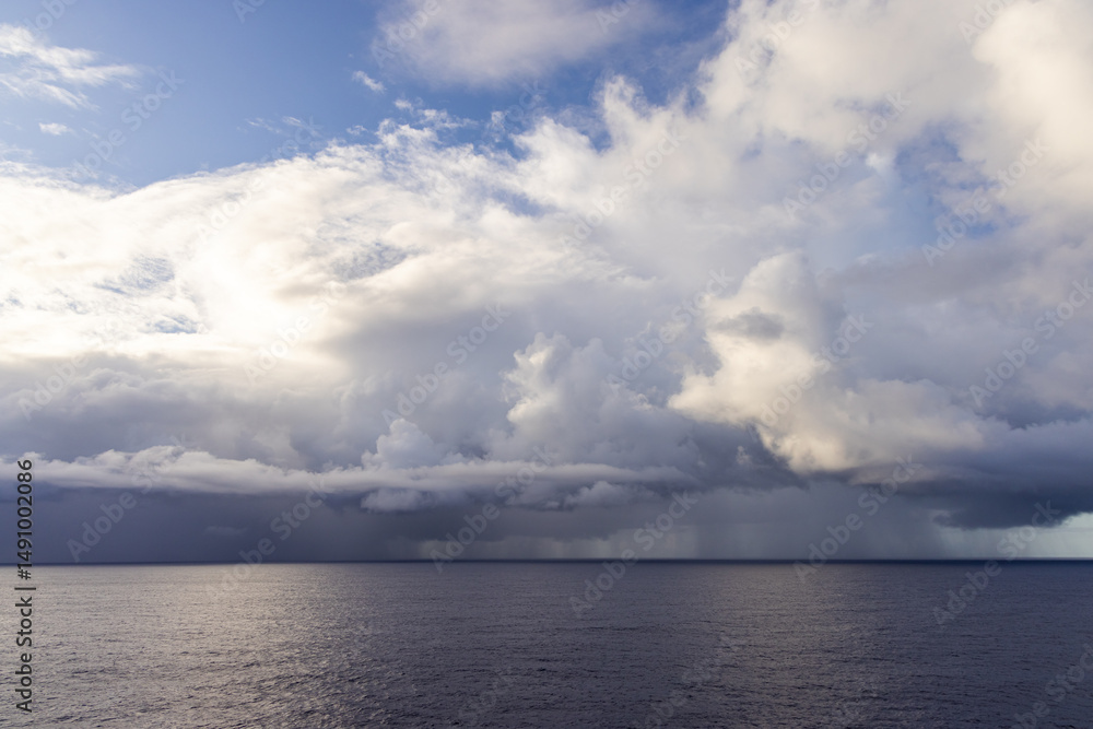 Obraz premium Dramatic Cloudscape Over Tranquil Ocean Waters Under a Bright Sky