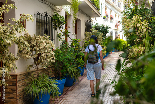 Woman walking through a traditional Andalusian village street with potted plants