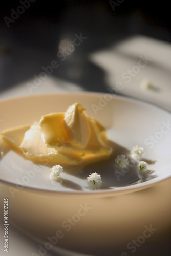 Soft butter in sunlight with white decorative flowers on a ceramic plate
Minimalist food styling image of soft butter served on a white plate with delicate white flowers and warm natural light. Ideal