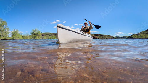 senior paddler is paddling decked expedition canoe on a mountain lake in Colorado, low angle, water level view