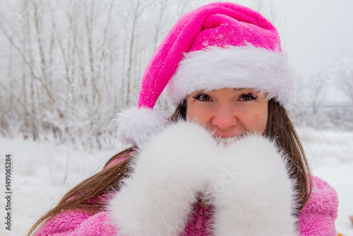 Girl in a pink Christmas hat in a winter forest