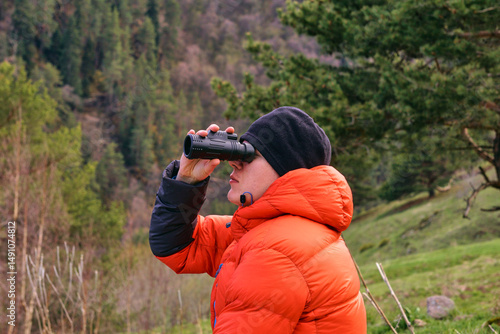 Foto A man looks intently at the mountains through a monocular