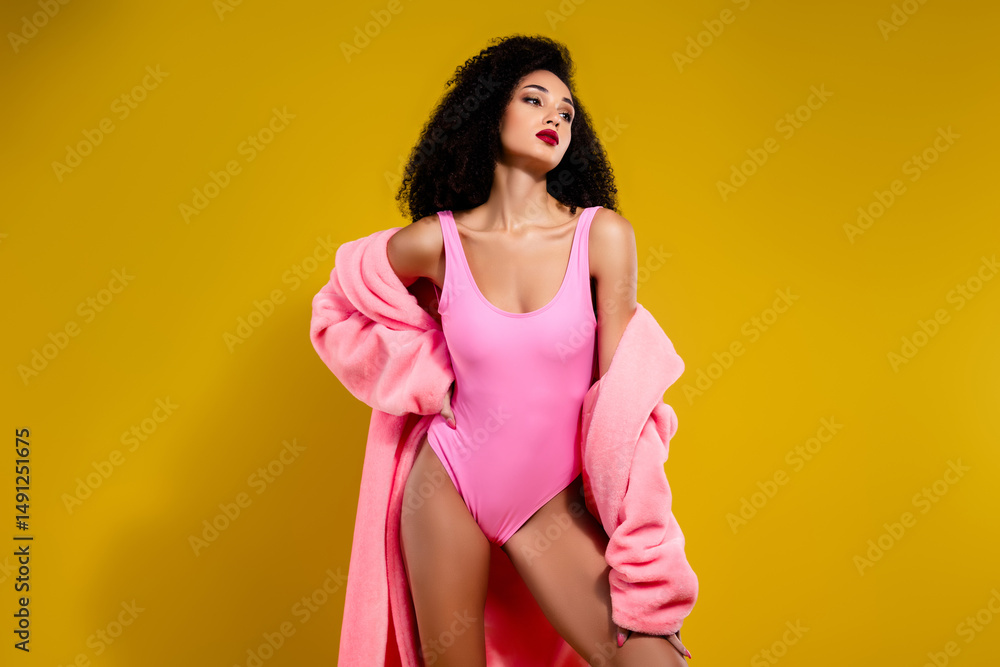 Obraz premium Elegant woman in pink swimwear with matching coat on bright yellow background, exuding glamour, sensuality, and style