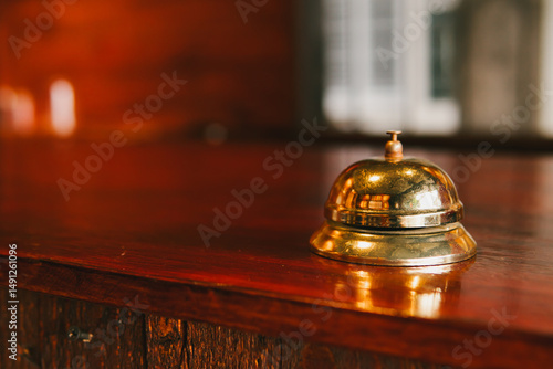 Obraz na plátně Vintage brass reception bell on wooden counter in an elegant lobby setting with