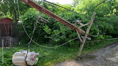 Power line completely destroyed by a fallen tree following severe storms and high winds. The wooden pole has been snapped in half created dangerous conditions and a power outage. Midwest, USA.