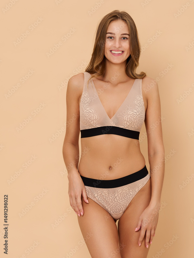 Naklejka premium Girl model in underwear posing in studio on beige background.