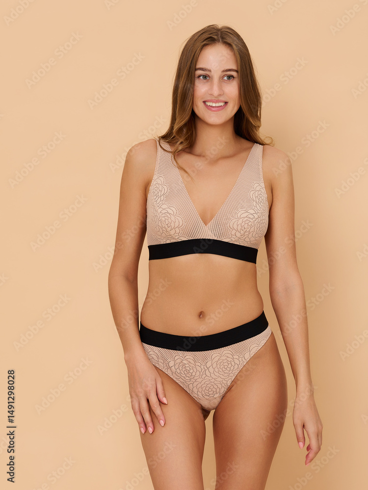 Fototapeta premium Girl model in underwear posing in studio on beige background.