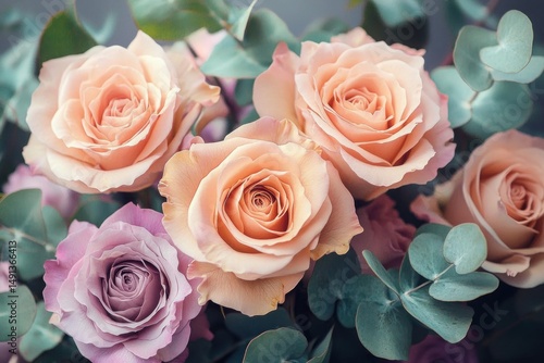 Close-up view of a bouquet featuring soft peach and light violet roses surrounded by silvery eucalyptus leaves, evoking a gentle and romantic atmosphere