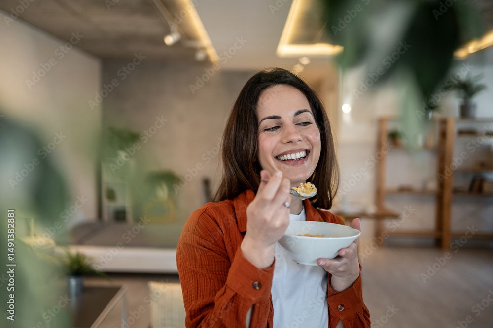 Happy woman enjoying breakfast cereal at home Happy woman enjoying breakfast cereal at home
