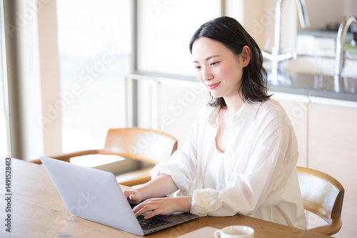 Foto パソコンを見ながら考える女性　ECサイトでの買い物などのイメージ