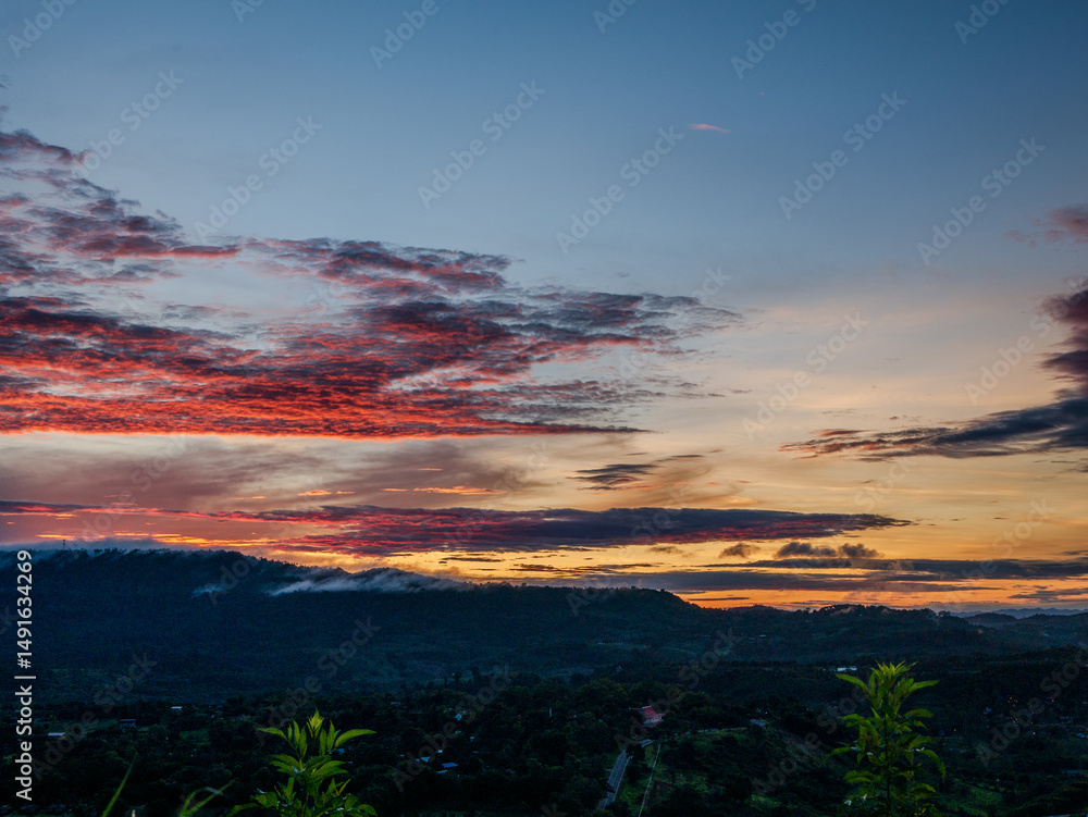 Fototapeta premium Scenic view dramatic beautiful sunset sky. Natural Sunset Sunrise on meadow silhouette shadow dark land. Vibrant dramatic sky on sunset, dawn, sunrise in Countryside. Landscape Colorful Sky At Sunset
