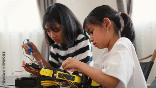 Wallpaper Mural Two Asian girls working together on robotics project at home. Promoting STEM education, teamwork, coding, and problem-solving through hands-on engineering and creative learning. Torontodigital.ca
