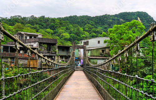 Jingan Suspension Bridge stretches across the Keelung River in the hillside village of Shifen, New Taipei, Taiwan. This pedestrian bridge connects both sides of the river and offers a view of rustic