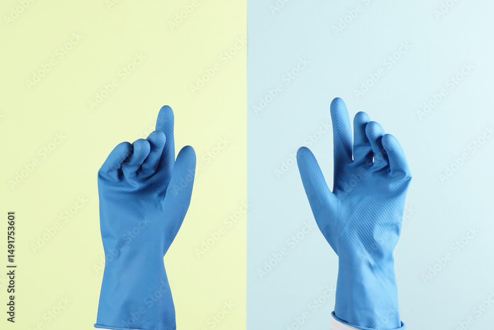 Obraz premium Hands with rubber gloves for cleaning on a blue-yellow pastel background