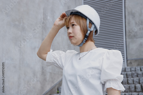 ヘルメットをかぶった横顔の女性とコンクリートの壁背景
