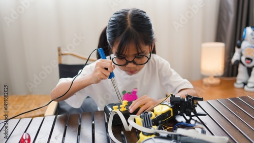 Wallpaper Mural Asian girl assembling robot parts at home, learning STEM and electronics. Developing engineering skills, logical thinking, and problem-solving through hands-on coding education for kids. Torontodigital.ca