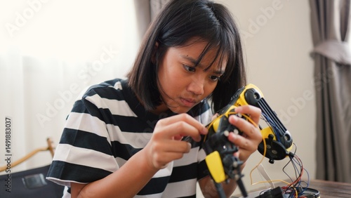 Wallpaper Mural Asian girl assembling robotic arm at home. Promoting STEM education, coding, engineering, and problem-solving skills. Hands-on tech learning for future innovators and young engineers. Torontodigital.ca