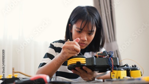 Wallpaper Mural Asian girl assembling robotic arm at home. Promoting STEM education, coding, engineering, and problem-solving skills. Hands-on tech learning for future innovators and young engineers. Torontodigital.ca