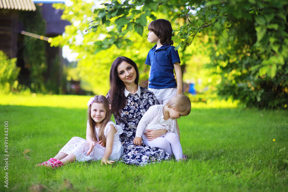 Young large family on a summer morning walk. Beautiful mother with children is playing in the park. Young large family on a summer morning walk. Beautiful mother with children is playing in the park.