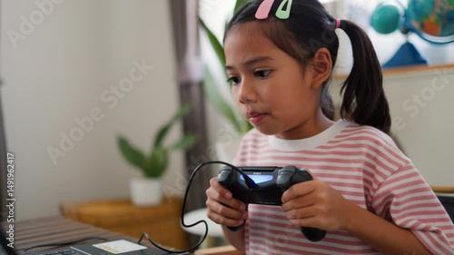 Asian teenage girl using game controller while talking during online gaming session at home. Concept of digital communication, live streaming, and modern tech lifestyle for teens.