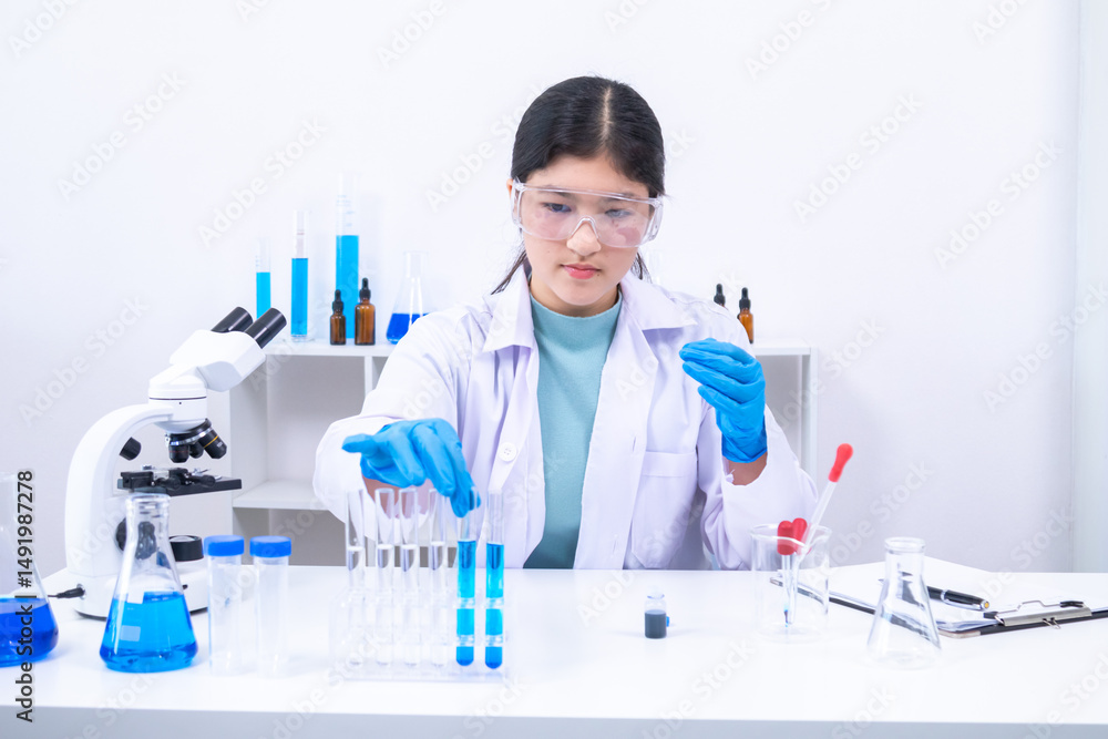 Fototapeta premium Female teen scientist holding test tubes and analyzing substance in clinical lab. Science, laboratory, scientist, experiment, and research represent accuracy, curiosity, and study atmosphere.