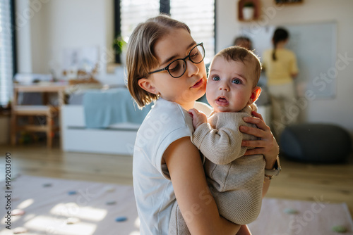 Big sister holding small little brother in her arms, taking care.