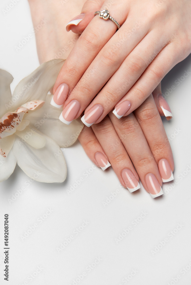 Woman showing french manicure and white orchid flower Woman showing french manicure and white orchid flower