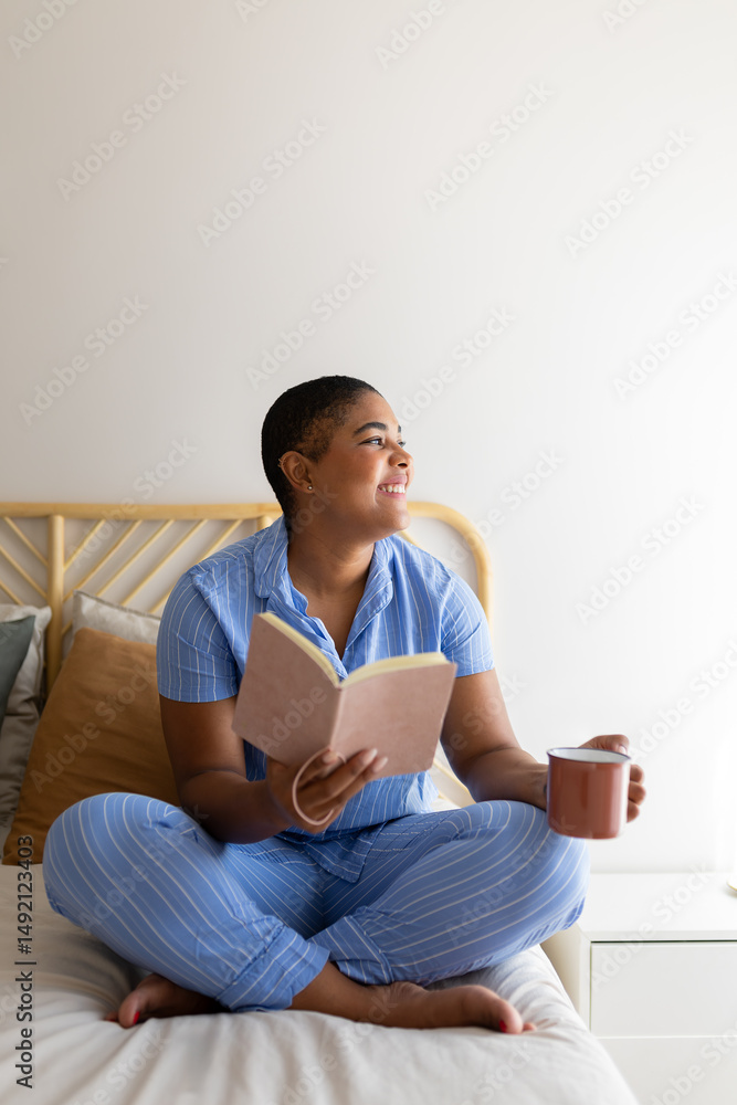 Obraz premium Serene woman enjoying morning coffee and book in bed