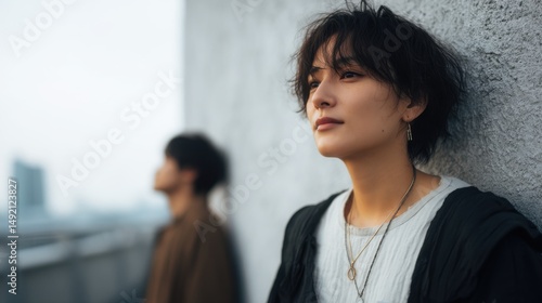 Couple enjoying a moment of reflection on a city rooftop at dusk, showcasing the serene atmosphere and urban skyline in the background