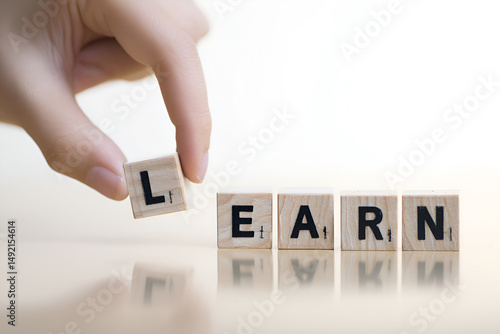 Conceptual image showcasing the creation of the word 'LEARN' with wooden letter blocks and hand