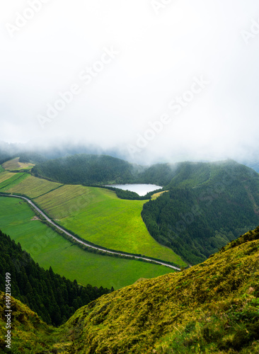 A bright lake nestled among green forested hills, visible from high above