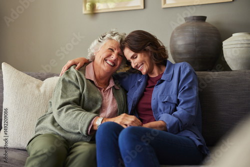 Foto Loving and happy mother embracing adult daughter on couch at home