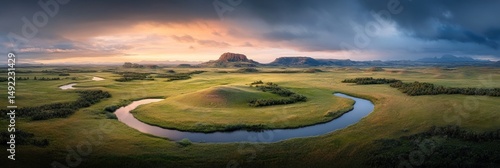 Scenic sunset over meandering river, rolling hills, and dramatic clouds