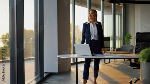 Confident businesswoman in modern office looking out the window. Concept of leadership, success, ambition, and corporate lifestyle.