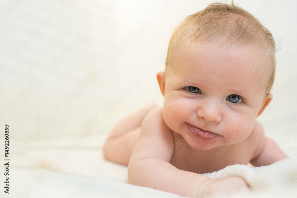 Smiling baby lying on bed in bedroom looking at camera. Adorable naked baby lying on stomach. Happy baby morning. Smiling baby lying on bed in bedroom looking at camera. Adorable naked baby lying on stomach. Happy baby morning.