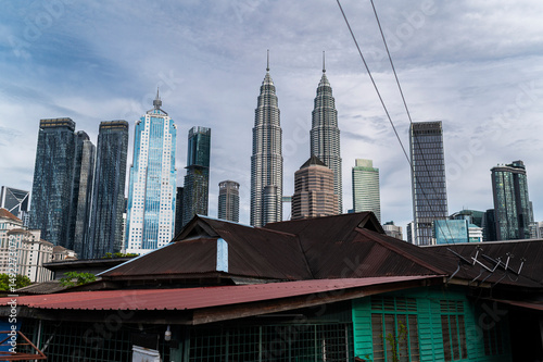 Rusty rooftops and teal house under Petronas Towers skyline, Kuala Lumpur, Malaysia