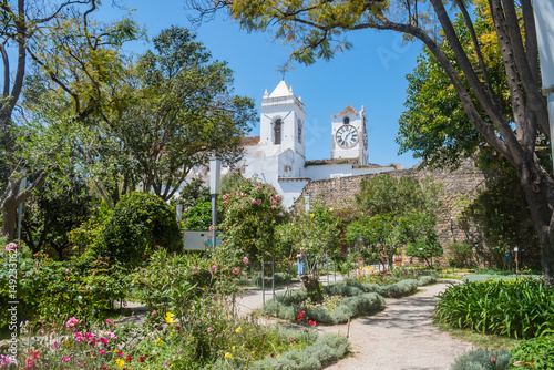 Flowers and trees in the garden of Tavira Castle with towers of the Santa Maria do Castelo church, PORTUGAL