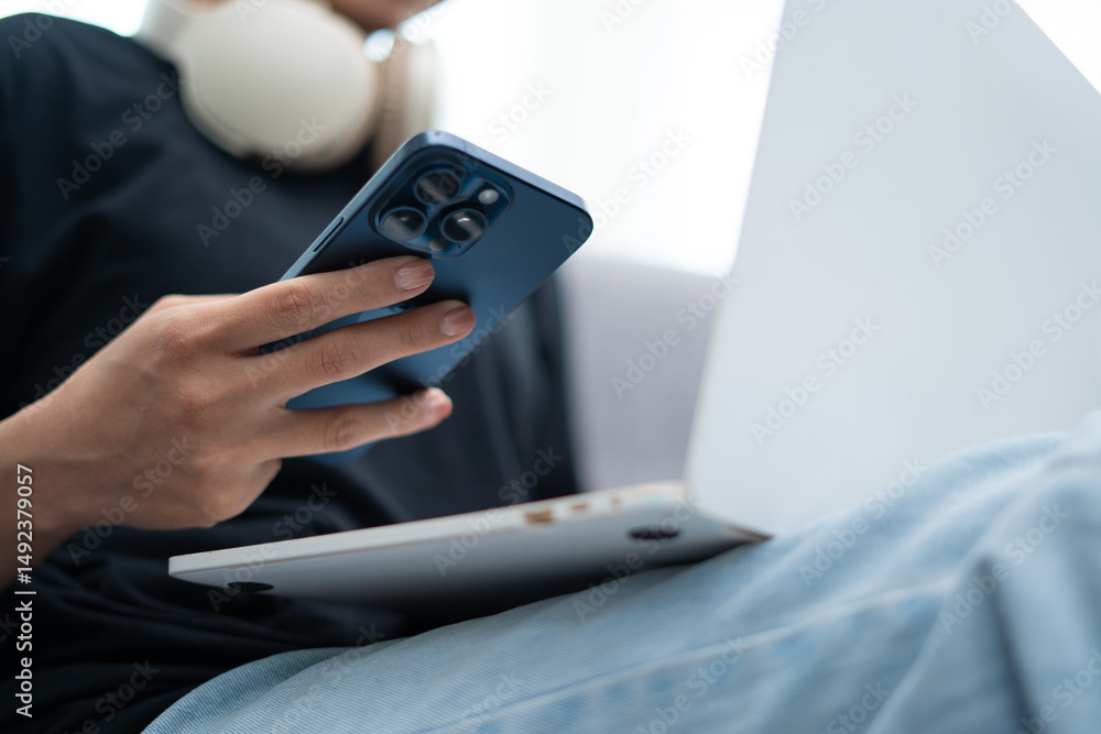 Close-up view of woman working from home using smartphone and laptop through internet communication network technology and e-commerce marketing. Close-up view of woman working from home using smartphone and laptop through internet communication network technology and e-commerce marketing.